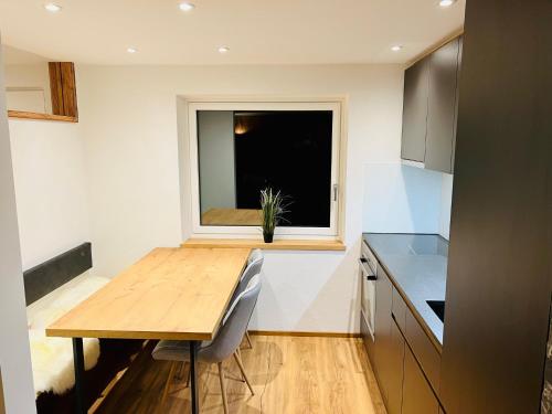 kuchnia z drewnianym stołem i oknem w obiekcie Schöne Wohnung mit Ausblick, Sauna und Hot-Pot in Westendorf, Tirol w mieście Westendorf