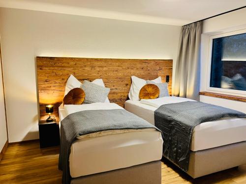 sypialnia z 2 łóżkami i drewnianym zagłówkiem w obiekcie Schöne Wohnung mit Ausblick, Sauna und Hot-Pot in Westendorf, Tirol w mieście Westendorf