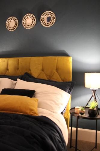 a bed with a yellow headboard and three plates on the wall at The Velveteen Townhouse in Colchester
