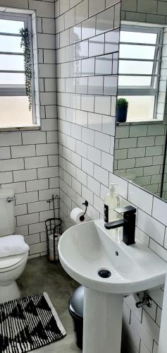 a white bathroom with a sink and a toilet at Bellas Cottage in Langebaan