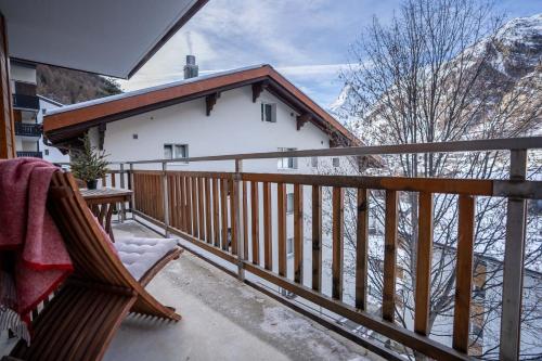 a balcony with a wooden railing and a house at Modern apartment with Matterhorn view in Zermatt