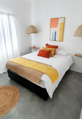 a bedroom with a large bed with a yellow and white blanket at Bellas Cottage in Langebaan