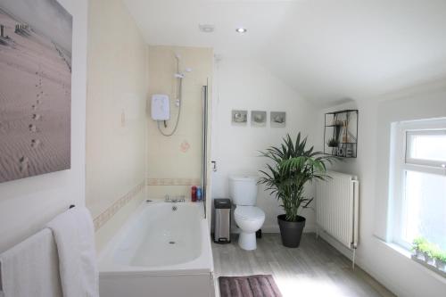 a bathroom with a tub and a toilet and a sink at Three Bedroom Townhouse - Free Local Parking - by Property Promise in Cardiff