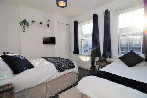 a bedroom with two beds and two windows at Three Bedroom Townhouse - Free Local Parking - by Property Promise in Cardiff