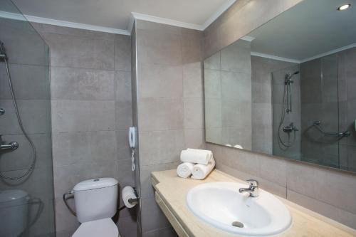 ein Badezimmer mit einem Waschbecken, einem WC und einem Spiegel in der Unterkunft Hotel Niriides Beach in Kolymbia