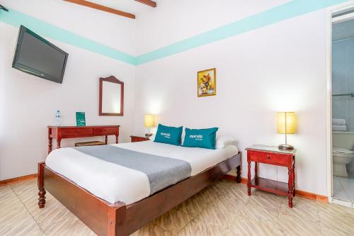 a bedroom with a bed and a toilet and a tv at Hotel Puerta del Sol Popayan in Popayan