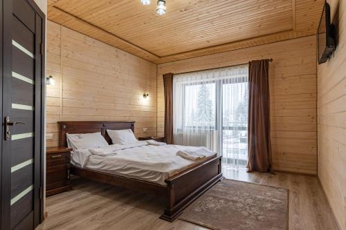 a bedroom with a bed and a large window at Madison in Bukovel