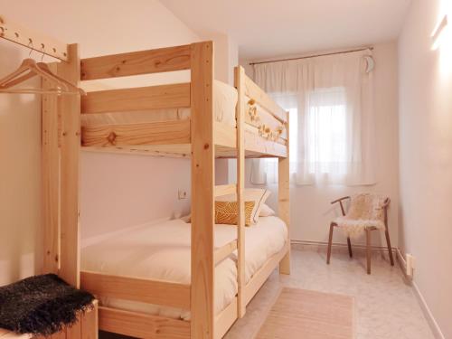 - une chambre avec 2 lits superposés et une chaise dans l'établissement Apartament Natura amb Calma, à Olot