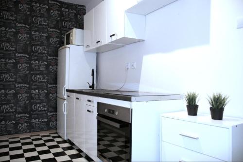 a kitchen with white appliances and a black and white checkered floor at Stilo Dom - ul Powstańców Śląskich in Wrocław