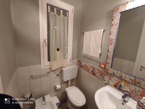 a bathroom with a toilet and a sink and a window at Case Vacanza Le Casette in Santo Stefano di Camastra