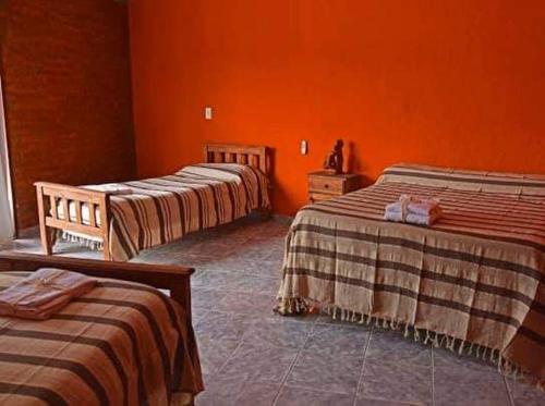 three beds in a room with orange walls at El Rancho Casa de Campo Exclusiva en Villa de Las Rosas Los impuestos que figuran en la publicación no se cobran in Villa de Las Rosas