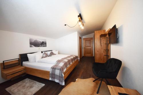 a bedroom with a bed and a chair in it at K-Appartements Klösterle in Klösterle am Arlberg
