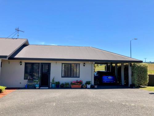 a white house with a car parked in the driveway at Almost Country in Taupo