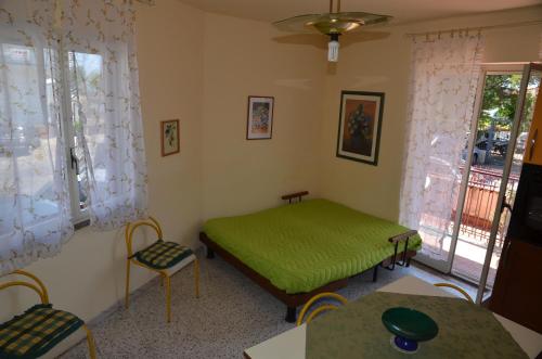 a bedroom with a green bed and a table and chairs at Casa Susanna in Fondachello
