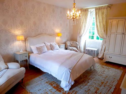 - une chambre avec un grand lit blanc et un lustre dans l'établissement Logis de Tirac, à Lorignac