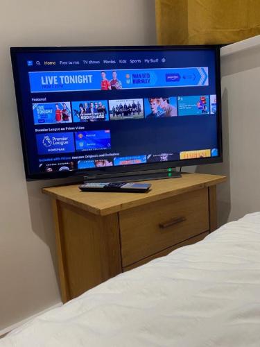 une télévision à écran plat installée au-dessus d'une table. dans l'établissement Double Bedroom with en-suite shower & free parking, à Belvedere