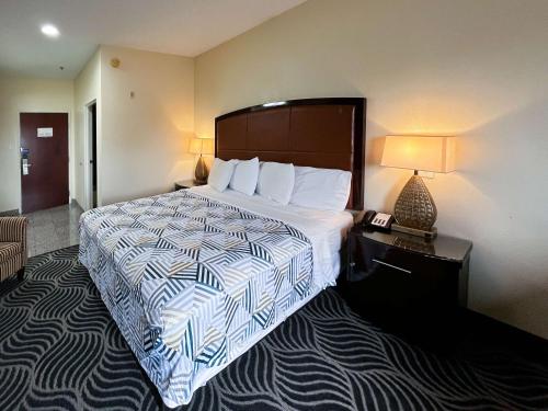 a hotel room with a large bed and a lamp at Executive Inn & Suites Breaux Bridge, LA in Breaux Bridge