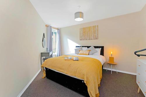 a bedroom with a large bed with a yellow blanket at Modern & Spacious 2 Bedroom Serviced Apartment Next to Lochend Park - Private Underground Parking & Lift Available - Close to Edinburgh City Centre in Edinburgh