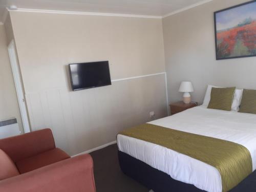 a hotel room with a bed and a chair at Fiesta Court Motel in Whanganui