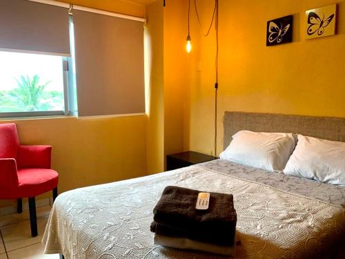 1 dormitorio con 1 cama y 1 silla roja en Andressa Mia Apartments, en Manzanillo