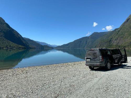 a camper van parked on the side of a lake at Base Puelo in Cochamó