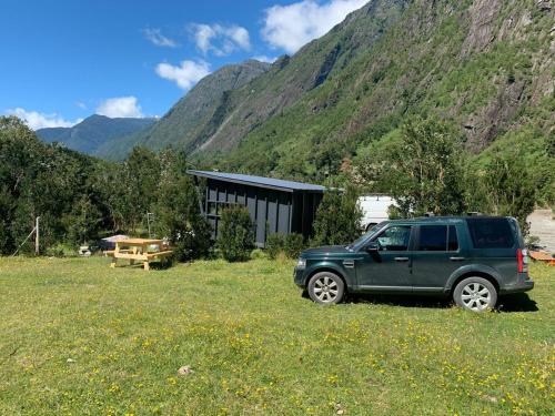 a green truck parked in a field in front of a mountain at Base Puelo in Cochamó