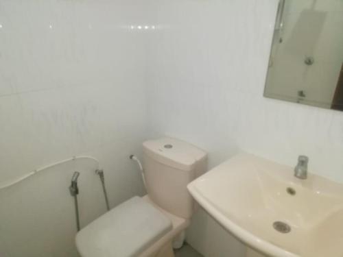 een witte badkamer met een toilet en een wastafel bij Beach Corner Weligama in Weligama