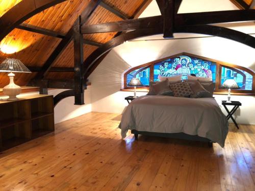 a bedroom with a large bed and a wooden ceiling at La Chapelle - The Library in Montagu