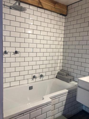 a white bath tub in a bathroom with white tiles at La Chapelle - The Library in Montagu