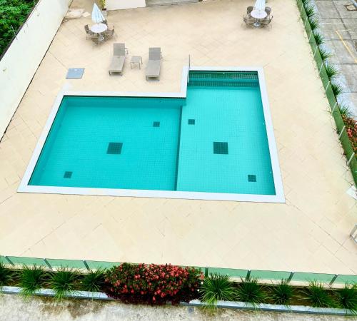 an overhead view of a swimming pool with chairs and flowers at Cobertura Duplex: piscina, três quartos e beira á mar in Ilhéus