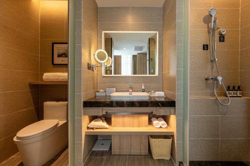 een badkamer met een wastafel, een toilet en een spiegel bij Atour Hotel Baoji Raiway Station Xingzheng Avenue in Baoji