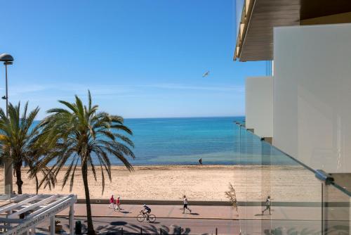 a beach with palm trees and people walking on the sand at Hotel Eden Palma Playa Adults Only in Can Pastilla