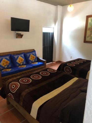 two beds in a room with a tv on the wall at Betos Departamentos in Valle de Bravo