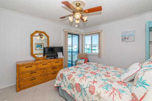 um quarto com uma cama, uma cómoda e uma ventoinha de tecto em Seaspray em Atlantic Beach