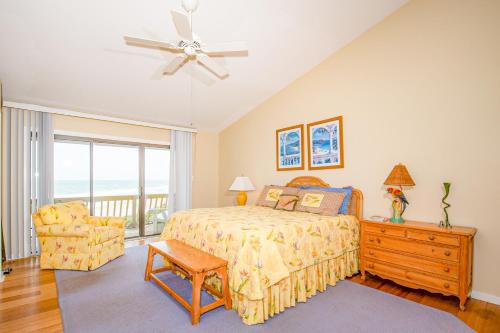 een slaapkamer met een bed en een stoel en een plafondventilator bij Ocean Grove in Pine Knoll Shores