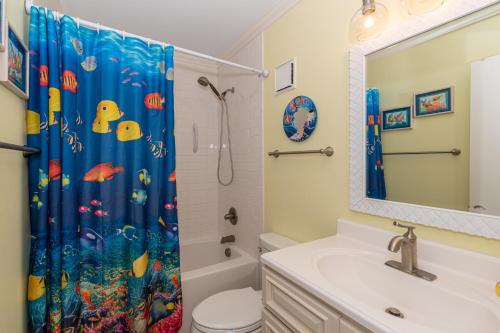 a bathroom with a sink and a shower curtain at Dunescape Villas in Atlantic Beach