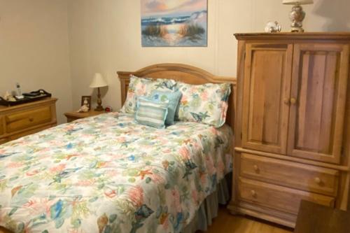 Schlafzimmer mit einem Bett und einem Holzschrank in der Unterkunft A Place At The Beach VI in Atlantic Beach
