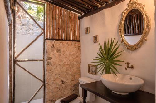 a bathroom with a sink and a toilet and a mirror at Playa Esperanza Tulum in Tulum
