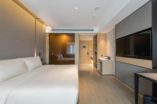 a bedroom with a large white bed and a television at Atour Hotel Quzhou Nankong in Quzhou
