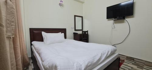 1 dormitorio con 1 cama blanca y TV de pantalla plana en Pashupati View Hotel en Katmandú
