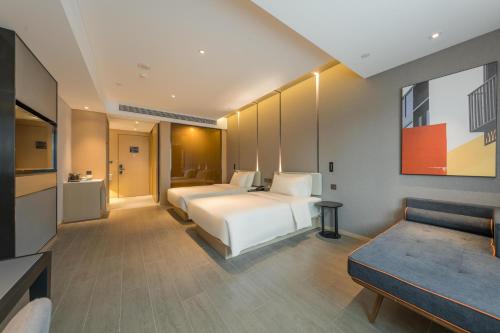 a hotel room with two beds and a couch at Atour Hotel Quzhou Nankong in Quzhou
