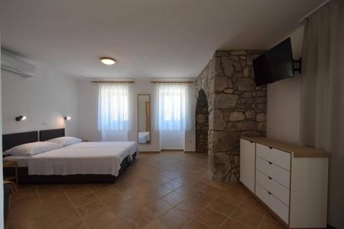 1 dormitorio con cama y pared de piedra en Apartments Insula Insule - rustic & peaceful, en Skrbčići