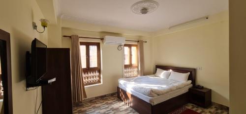 1 dormitorio con 1 cama, TV y ventanas en Pashupati View Hotel en Katmandú