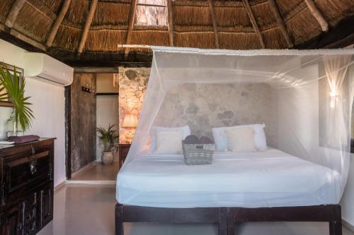 a bedroom with a white bed with a canopy at Playa Esperanza Tulum in Tulum