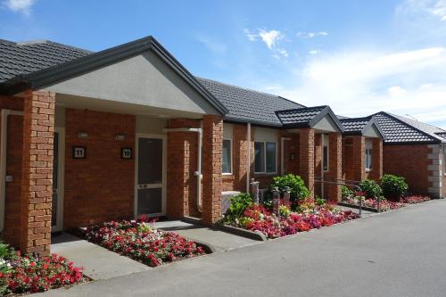 una fila de casas con flores delante de ellas en Northwood Motor Lodge, en Christchurch