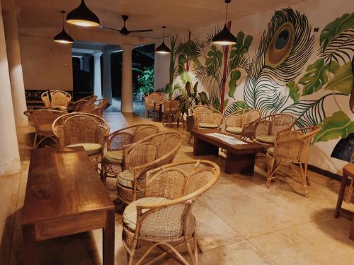 un ristorante con tavoli e sedie in legno e un murale di Alice in Paradise a Unawatuna