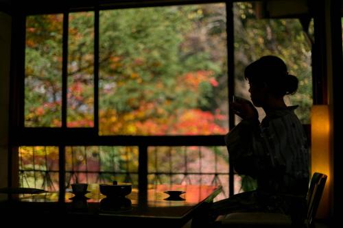 a woman sitting at a table looking out a window at Chousenkaku Kameya in Shimo-suwa