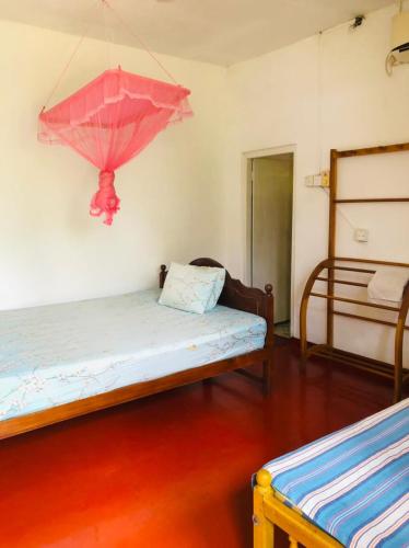 a room with two beds and a pink umbrella on the wall at Bole Guest Bentota in Bentota
