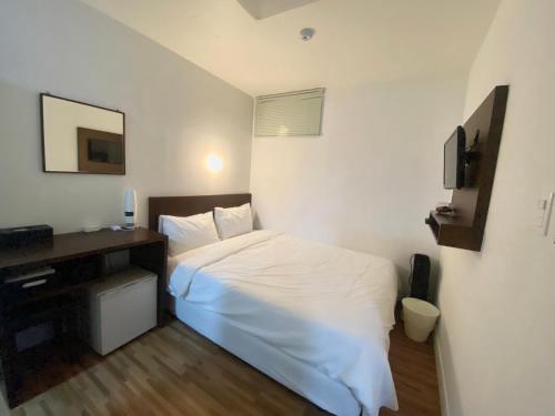 a bedroom with a white bed and a television at Ekonomy Haeundae Hostel in Busan