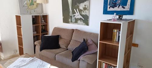 a living room with a couch and a book shelf at Ideal location Very spacious apartment in Maspalomas